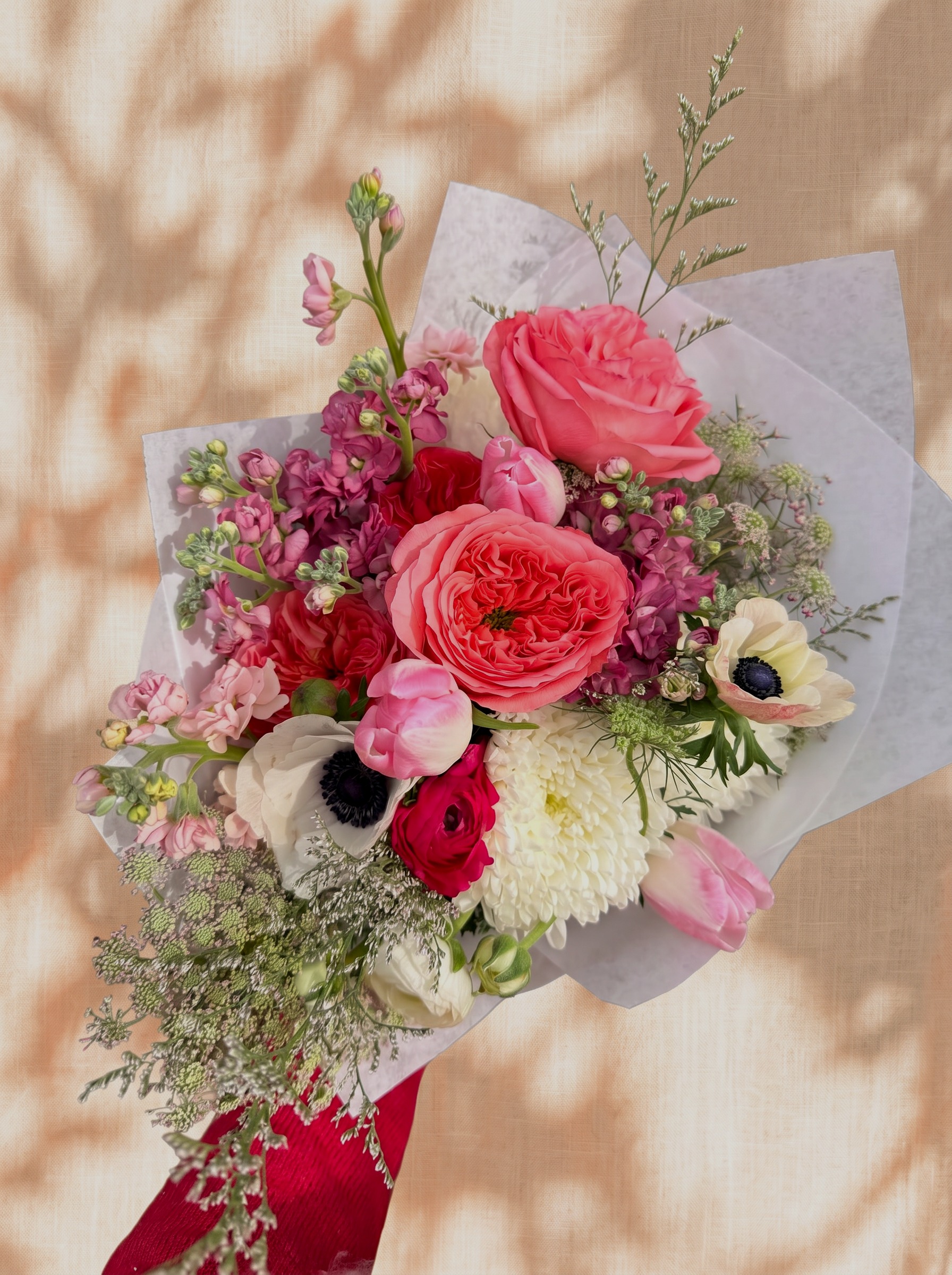 Coral garden roses, pink stock, anemones and chrysanthemum hand-tied bouquet