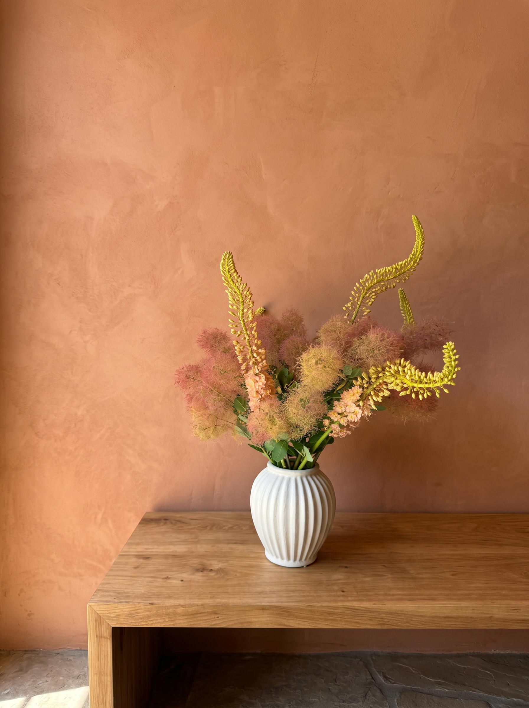 Coral smokebush and yellow eremurus in a fluted white vase