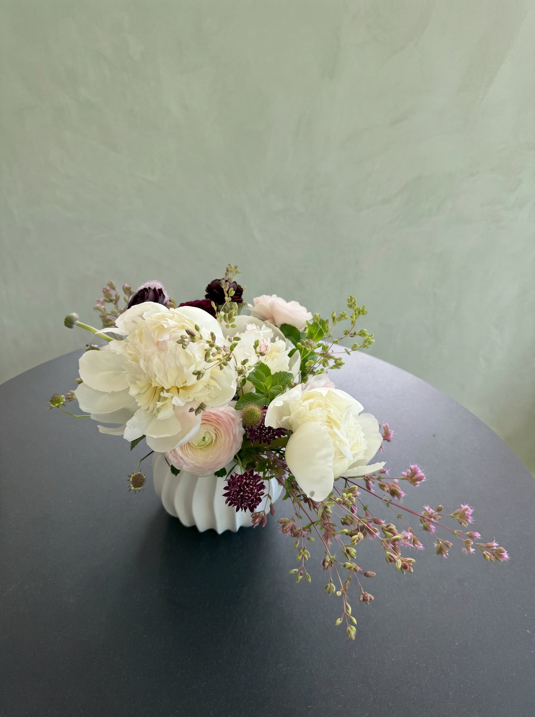 Ivory peonies and blush ranunculus in a fluted white bowl